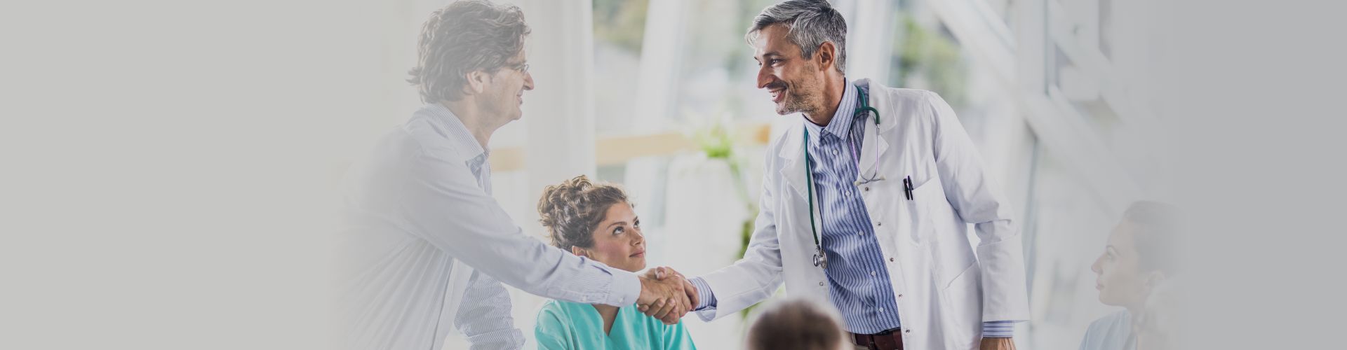 Doctors and nurses sitting at table and shaking hands